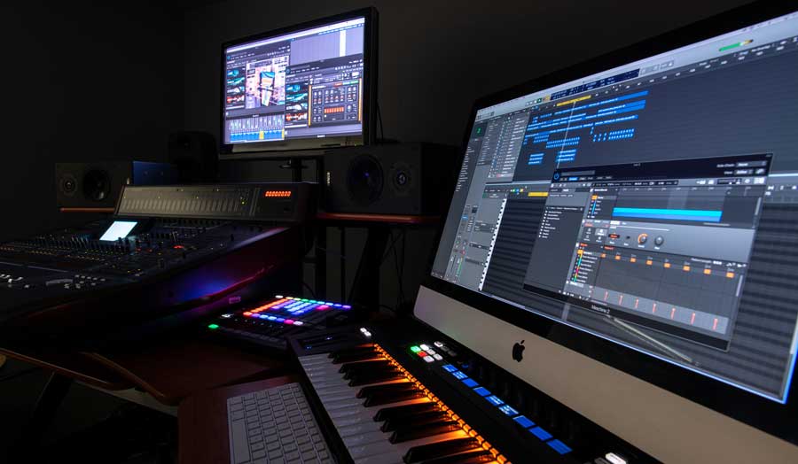equipment in a music surround sound studio, 2 screens, keyboards and mixing decks