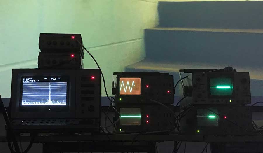3 pieces of sound recording equipment, all with screens of different sizes with different images on them, places at the bottom of concrete stairs