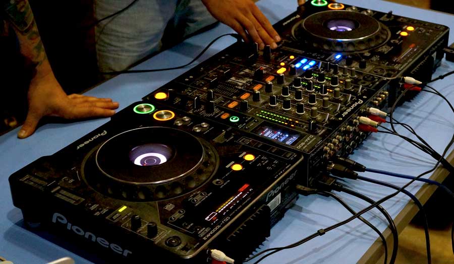 Hands on the dials of a dj mixing deck
