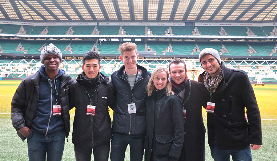 London Met students stand at the edge of the famous Twickenham turf, with the east stand in the back