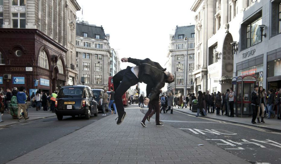 A young person doing a somersault in the middle of a shopping street