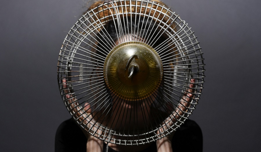 Image of electric fan held in front of woman's face.