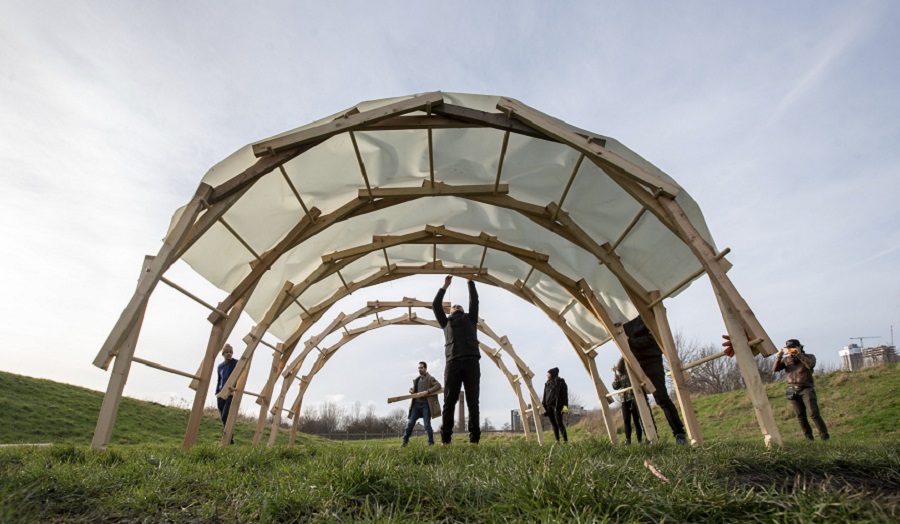 group of people under a large timber arch in a field