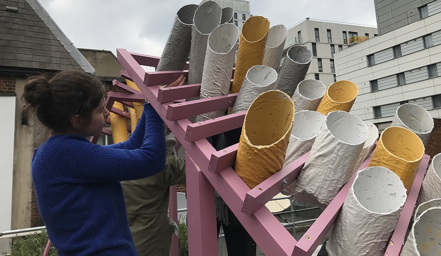 woman adjusts large structure made of pipes