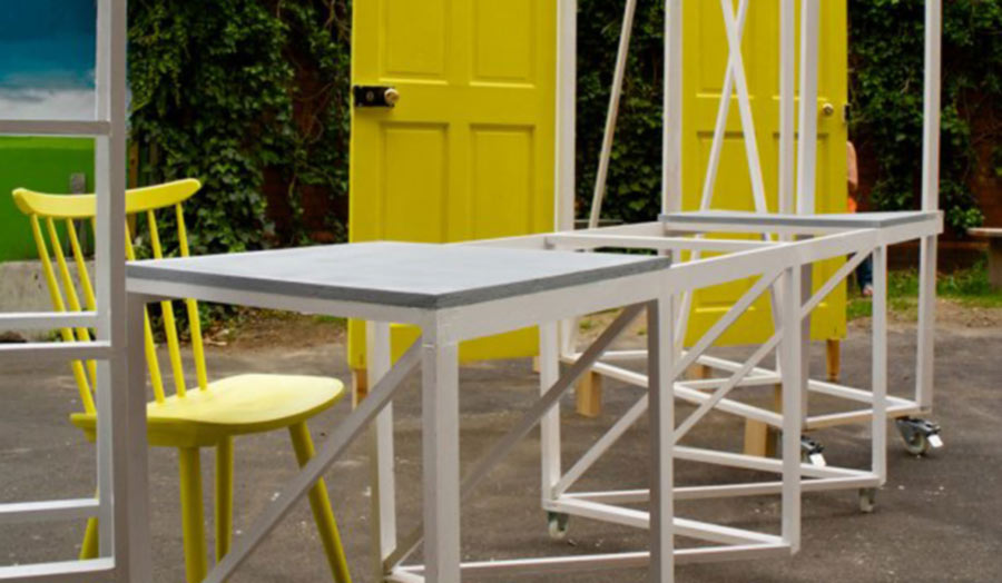 A set of folding tables and door-frames with yellow doors fitted in.
