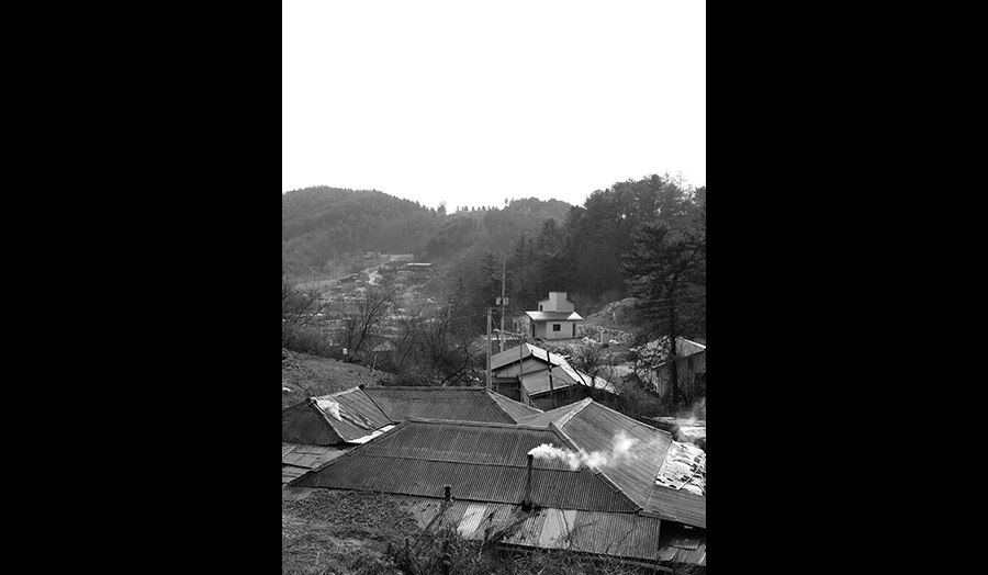 A view of A black and white photograph showing the rooftops of a village in a valley