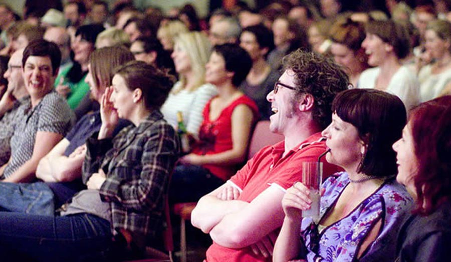A seated audience laughing
