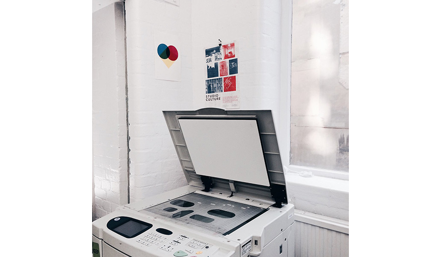 A digital printing machine in a corner of a room with its lid left open