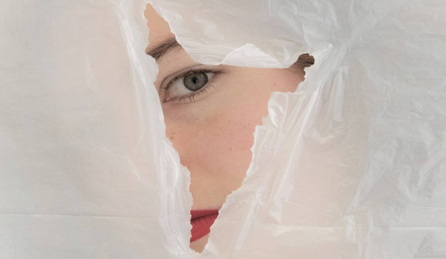 Half of a woman's face seen through a hole on a plastic sheet