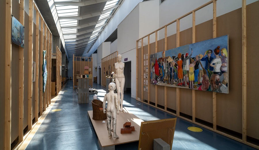 A long and narrow exhibition space with photography works on the walls and two mannequins