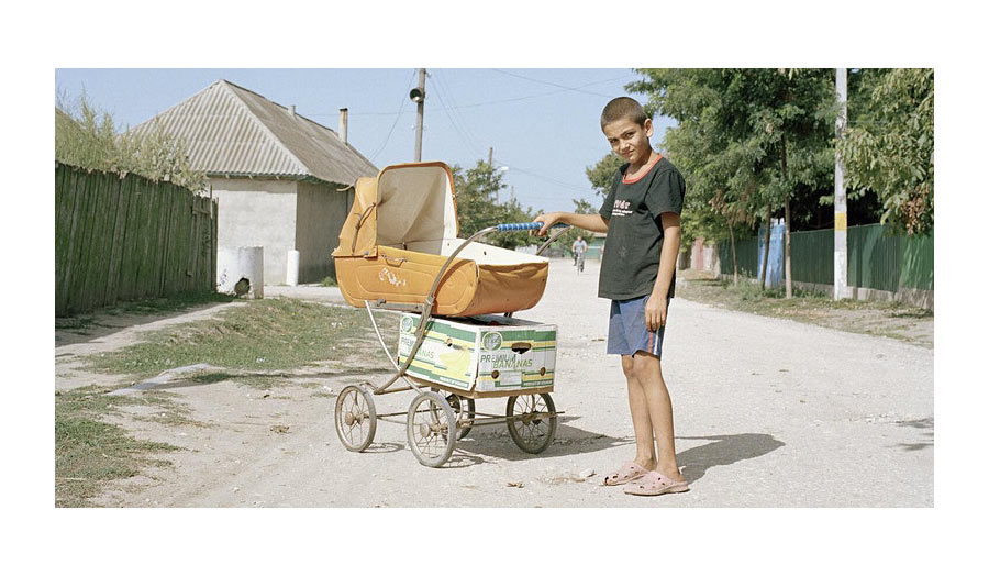 A boy with an antique pram on a rural street