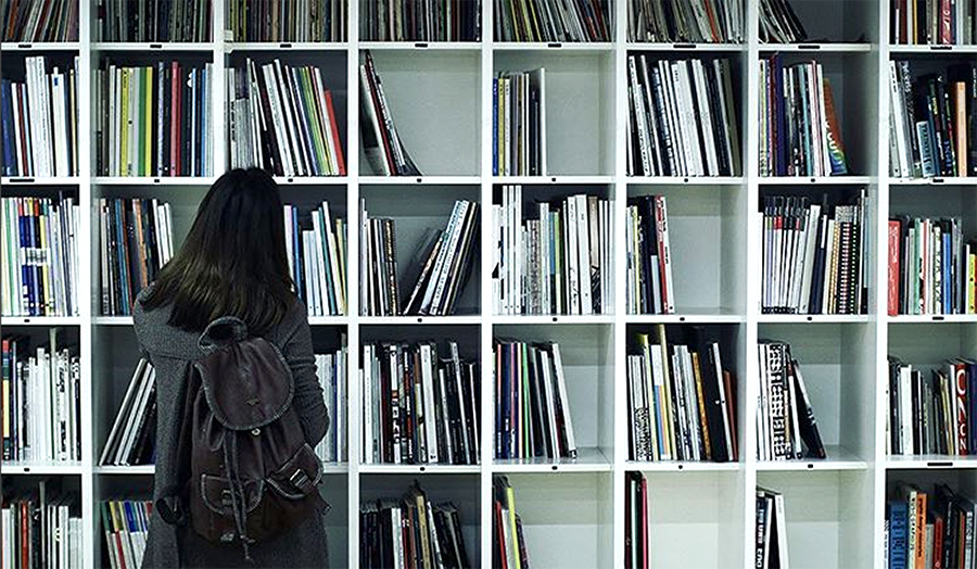 A student looking at a shelf of art and design books