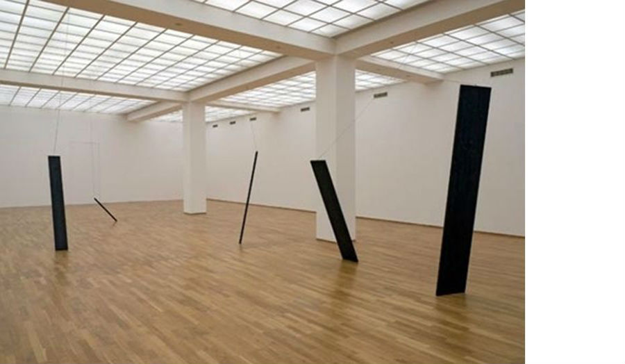 A gallery installation showing a series of rectangular materials at unusual angles