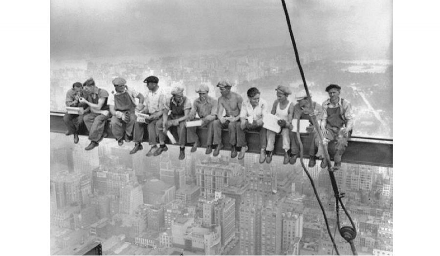 Old photo of workers taking a risky break sat on a crane high above a city