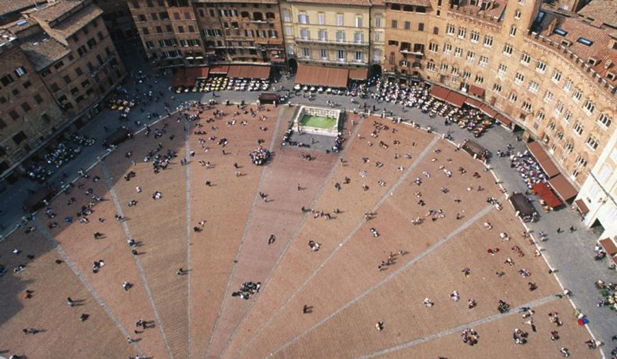 An aerial photo of a city square, full of people milling about.