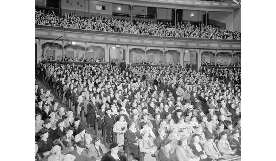 Black and white photograph of a crowd sitting in a theatre