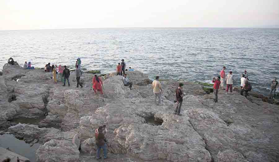 People standing on the rocks by the water at the beach