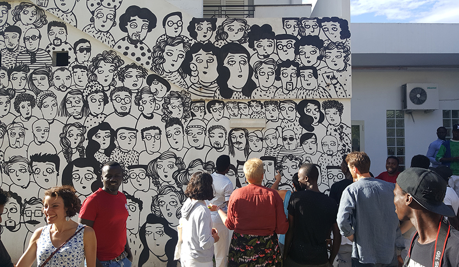 Italian refugee centre photo by James Rubio showing people seeing a wall of hand-drawn faces