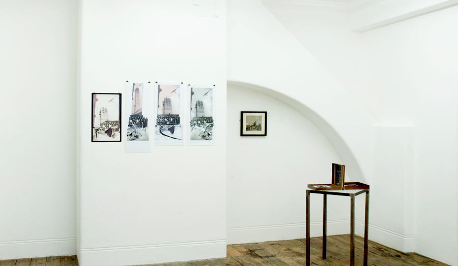 An exhibition space at Betts Gallery showing tall building artworks and table display