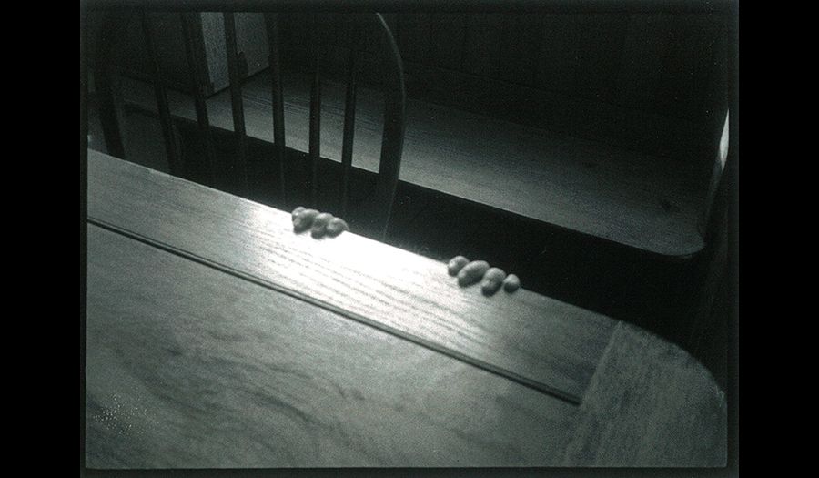 Wooden table and chair showing fingers clinging onto the table