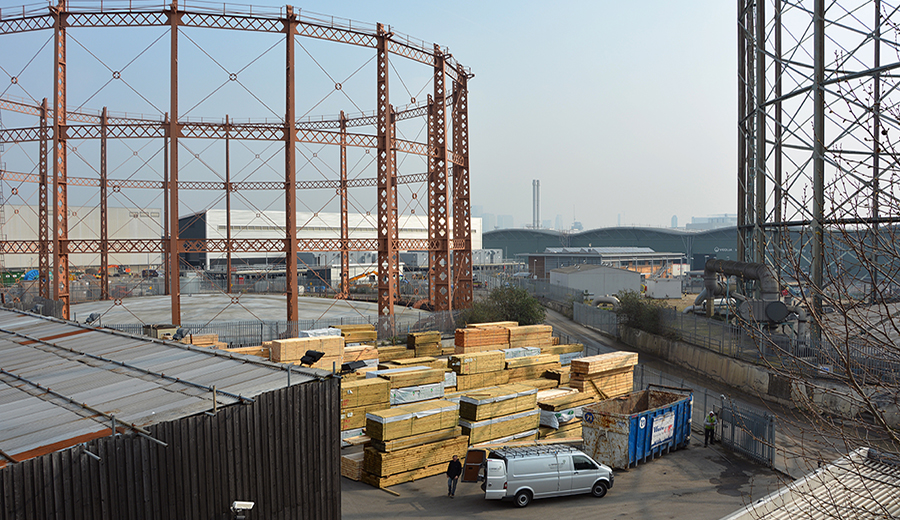 stacks of timber beside gasometers