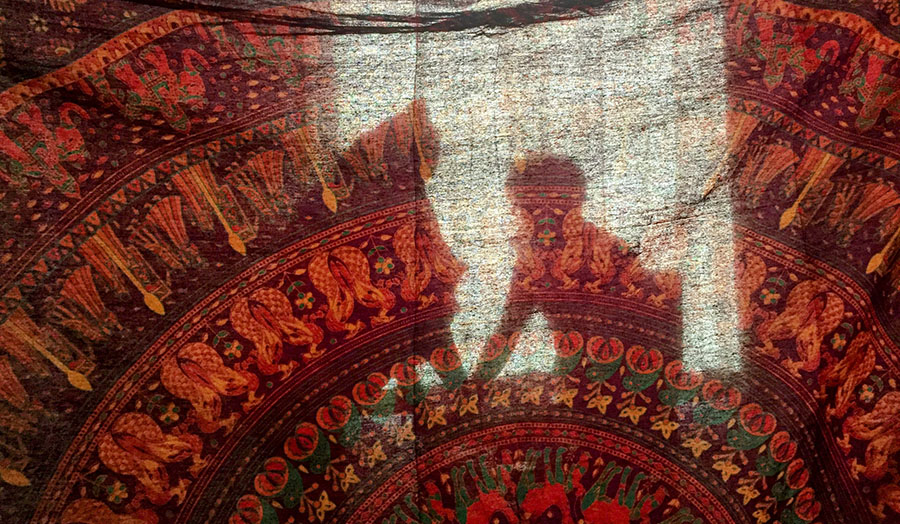 silhouette of child against window through Indian fabric