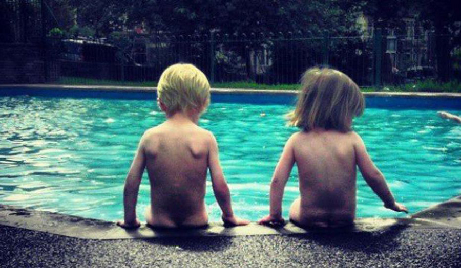 Image: Two children sitting by a swimming pool