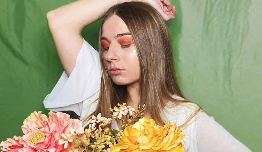 woman wearing bright eyeshadow holding flowers