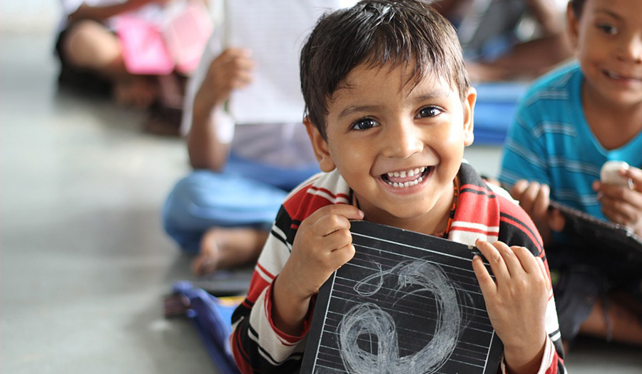 Boy smiles holding small chalkboard
