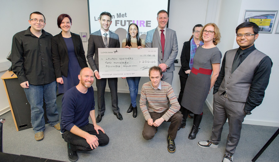 Student competition winner is presented with a large check surrounded by staff and event organisers