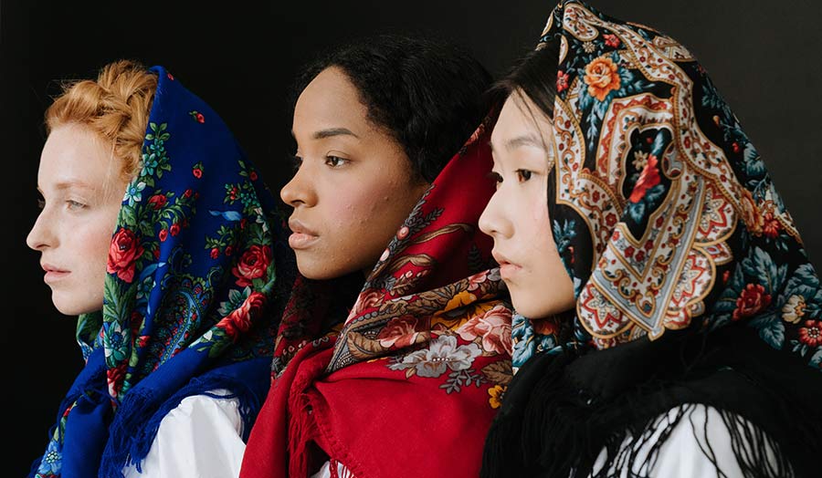 Three women of different cultural identities with a floral headscarf