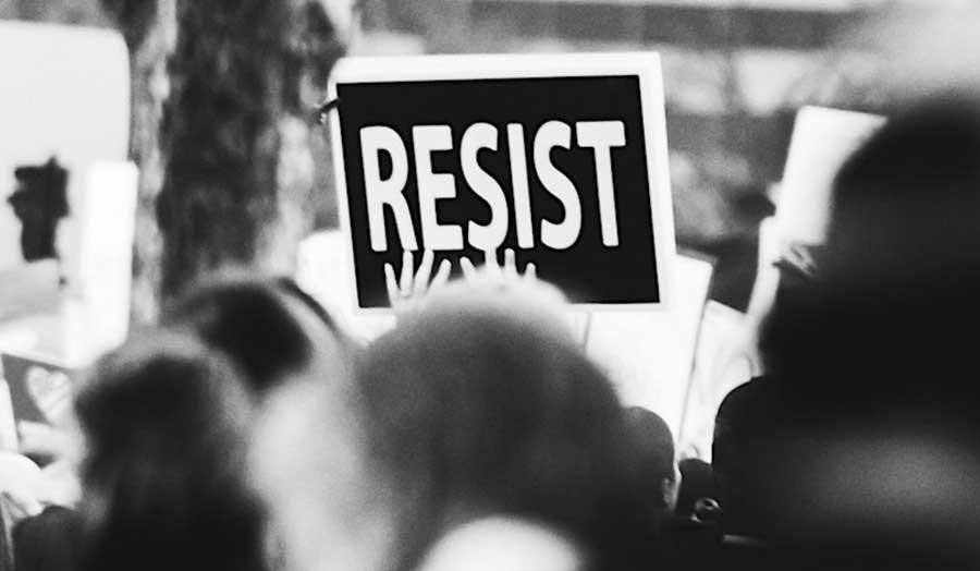 banner with words 'resist' written on it hold by two hands