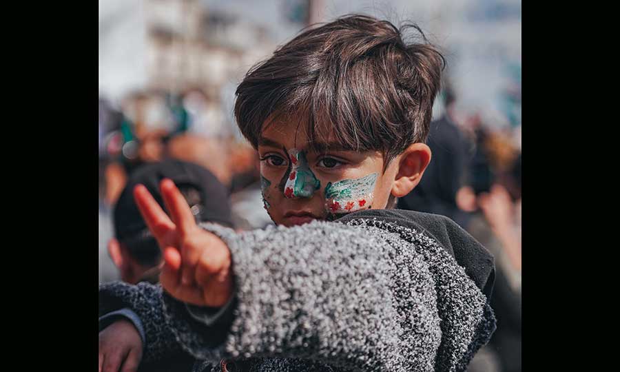 a boy with a Syrian flag painted on his face