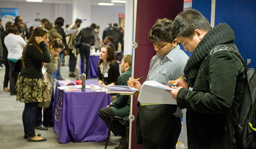 Two students writing down their notes at a career fair