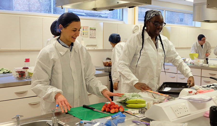 Two students chopping food in a London Met lab