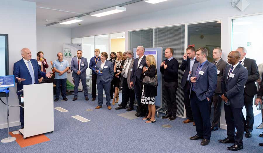 VC John Raftery speaking at the Cyber Security Research Centre launch event with 18 staff members and guests looking on from the right hand side