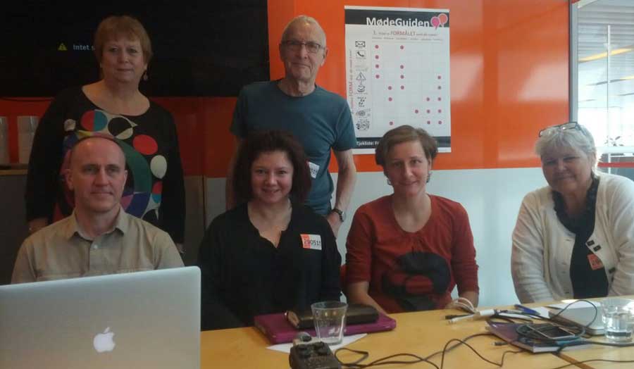 Four people sitting at a table with a laptop on it and two behind at a workshop in Copenhagen