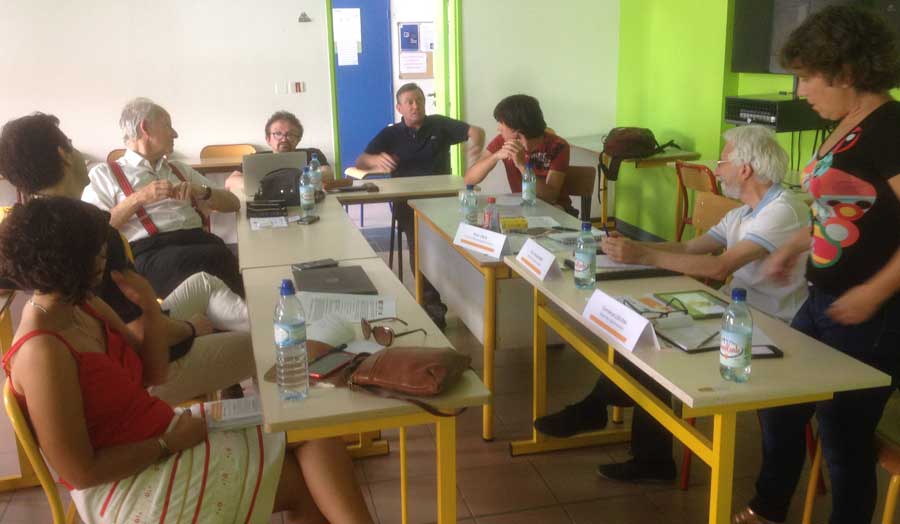 7 people sitting and 1 standing around a table at a workshop in Perpignan