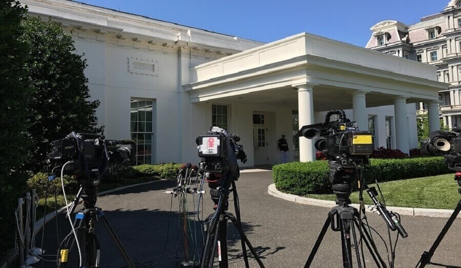 Front of the White House with several cameras and microphones set up in front of it