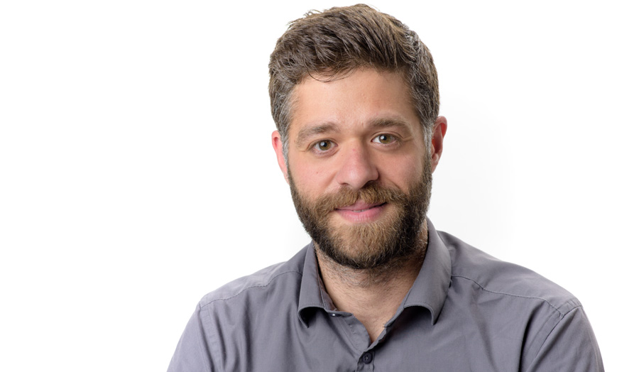 Short-haired and bearded male lecturer Dr Alexandros Chrysikos smiles to camera wearing a shirt.