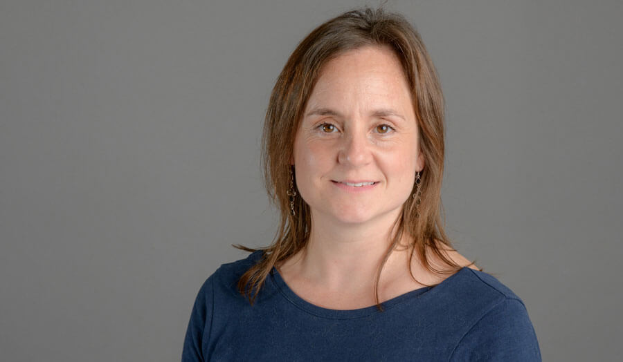 Long-haired female lecturer Cassandra Terry gazes to the camera with a smile.