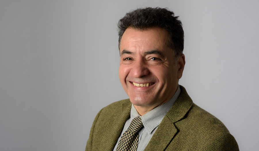 Dr Seyed Mortaza Vaezi-Nejad a male lecturer grins to camera against a grey background.