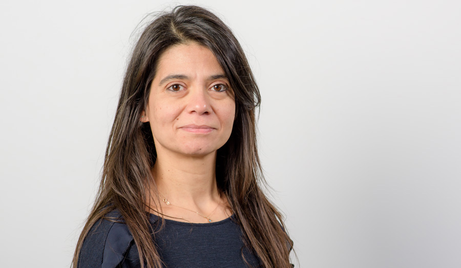 Long-haired female academic Dr Eirini Meimaridou smiles to the camera.