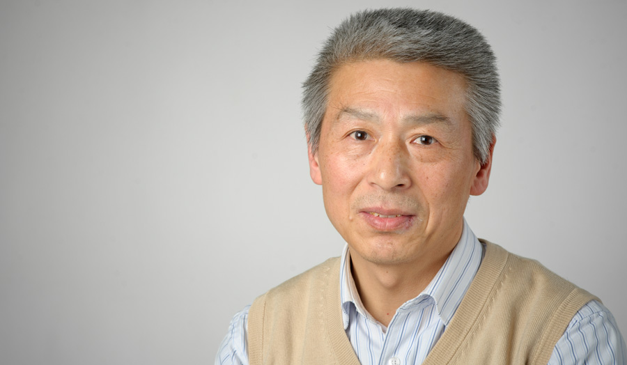 Dr Zhanyuan Hou smiles to camera as he poses against a grey background.