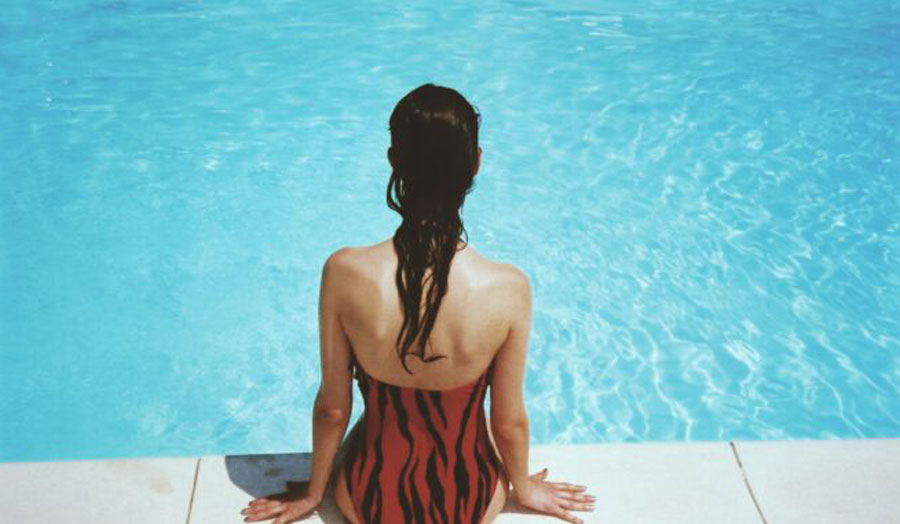 a woman sits on the edge of a pool