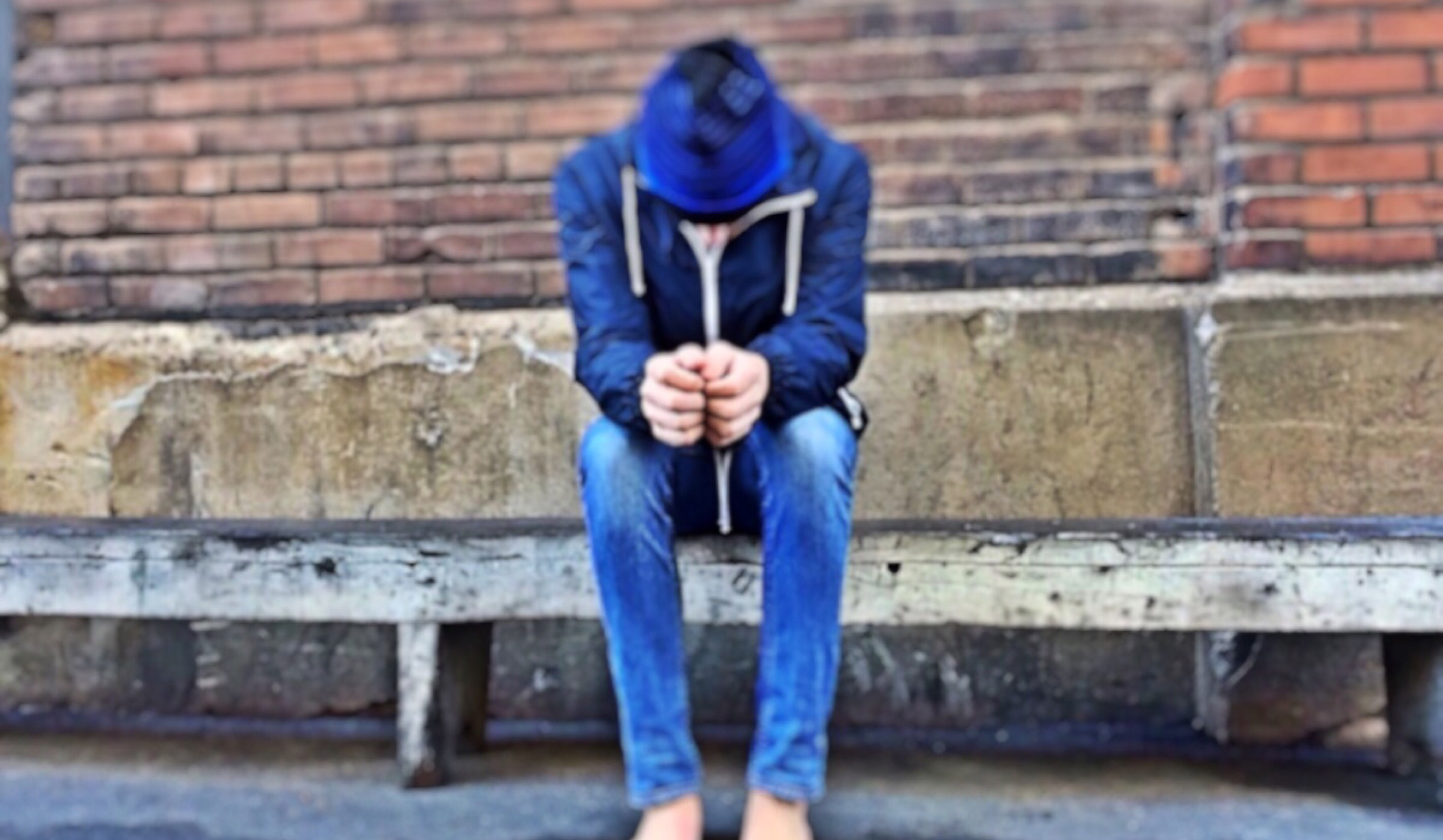 A man sitting on a bench with his head bent low