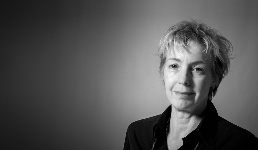 Jenny Harding, a female lecturer, poses in a black suit, smiling to camera.