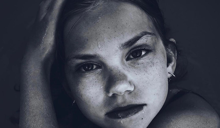 Black and white image of young girl with wet face staring towards camera