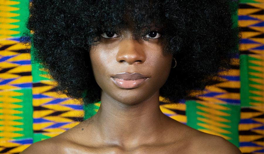 Close up portrait of a young black woman with an afro hairstyle and her bare shoulders  