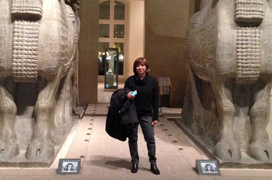 Fatemeh Safaii Rad standing between two ancient statues in a museum